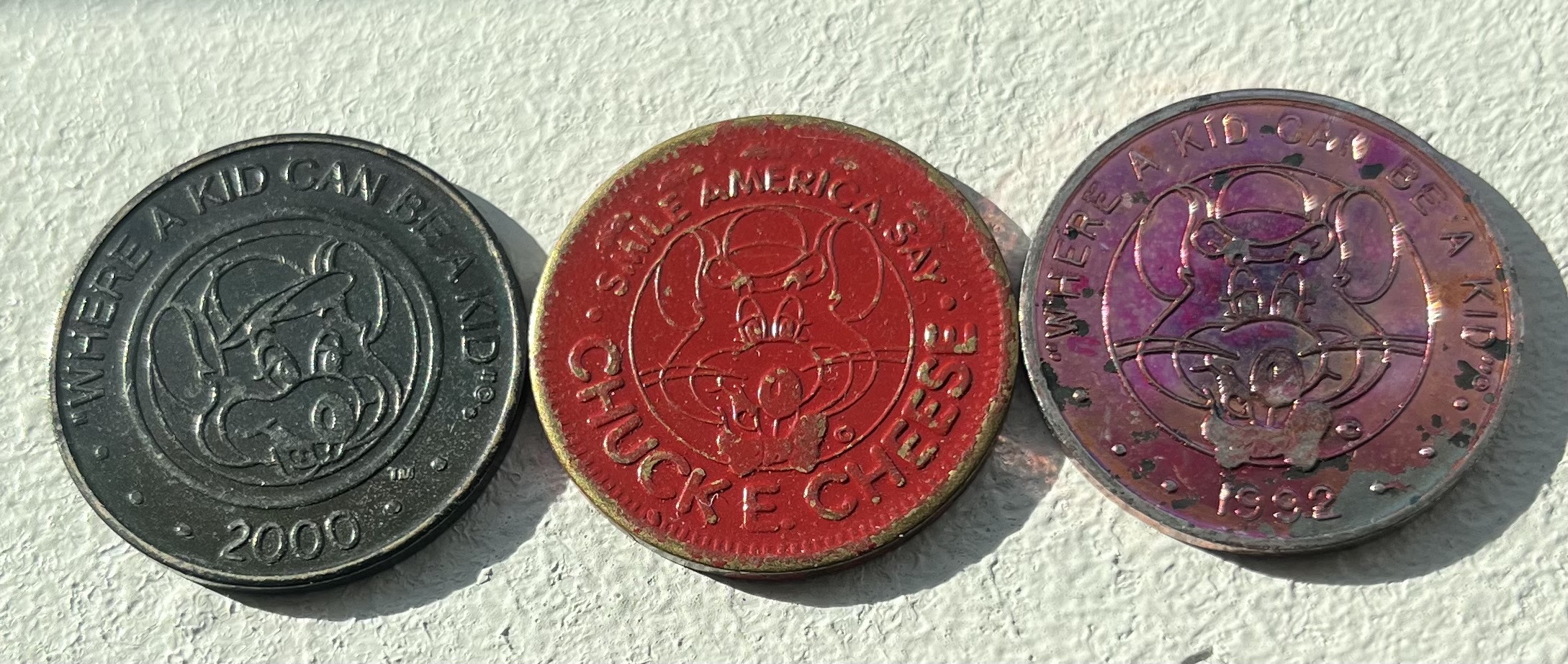 Chuck E. Cheese tokens with three different finishes